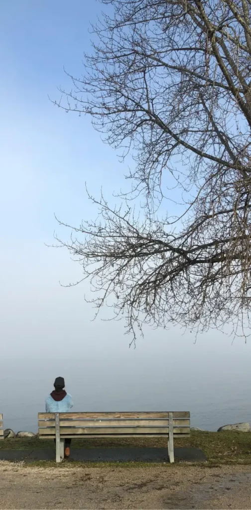 Woman sitting quietly on a park bench in contemplation overlooking the ocean